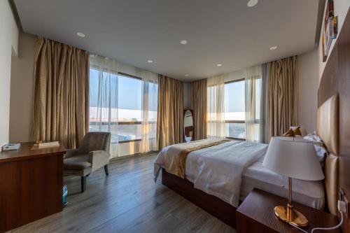 Habitación de hotel con cama, silla y ventanas en فندق روزالينا, en Yanbu