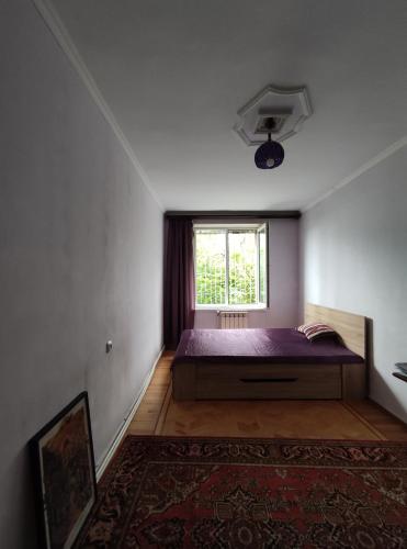 um quarto com uma cama roxa e uma janela em 1 Bedroom Cosy Apartment near Botanical Garden em Yerevan