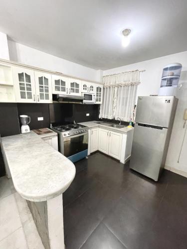 a kitchen with white cabinets and a stainless steel refrigerator at Casa con Habitaciones privadas in Guayaquil