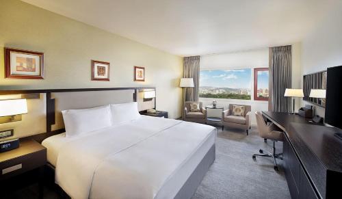 a hotel room with a large white bed and a desk at Transcorp Hilton Abuja in Abuja