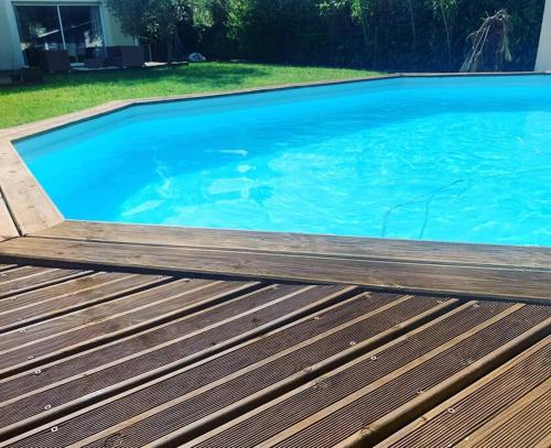 une grande piscine bleue avec une terrasse en bois dans l'établissement Maison 160m2 Eysines, à Eysines