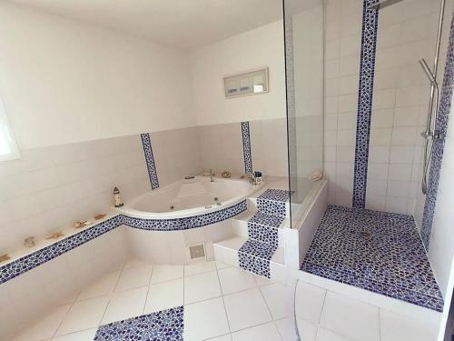 La salle de bains blanche est pourvue d'une baignoire et d'une douche. dans l'établissement Maison 160m2 Eysines, à Eysines