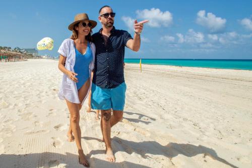 a man and a woman standing on a beach at Wyndham Grand Cancun All Inclusive Resort & Villas in Cancún