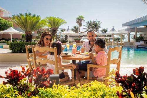 a family sitting at a table by the pool at a resort at Wyndham Grand Cancun All Inclusive Resort & Villas in Cancún