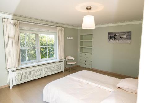 ein Schlafzimmer mit einem weißen Bett und einem Fenster in der Unterkunft De Boter Villa in Diksmuide