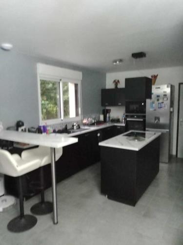 une cuisine avec des armoires noires et un comptoir blanc dans l'établissement Chambre chez l'habitant, à Paimpol