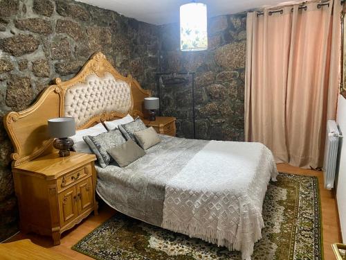 a bedroom with a bed and a stone wall at Casa Romã in Vale de Azares