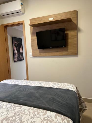 um quarto com uma cama e uma televisão de ecrã plano na parede em Flat Super Luxo - Rio Quente - Acesso Ao Rio em Rio Quente
