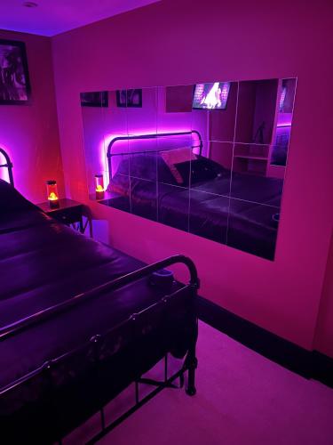 a room with two beds and a mirror with purple lights at The Indulging Basement in Barnsley