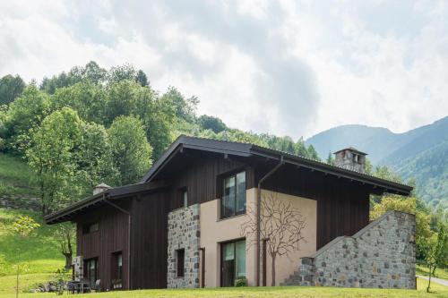a house in a field with mountains in the background at Quader nidi nel verde in Bienno