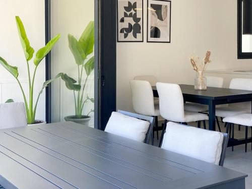 comedor con mesa negra y sillas blancas en Phaedrus Living White Hills Suites Panoramic View, en Aglantzia