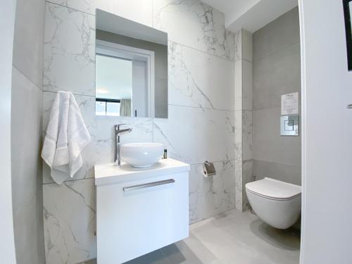 Baño blanco con lavabo y aseo en Phaedrus Living White Hills Suites Panoramic View, en Aglantzia