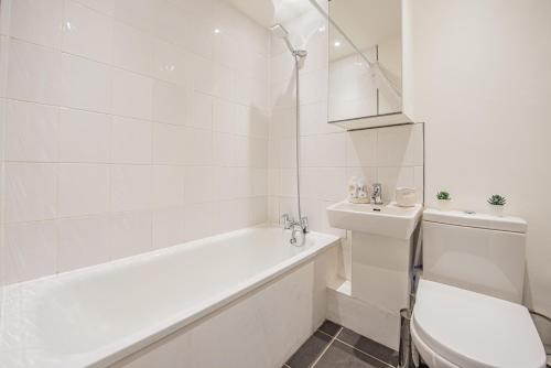 ein weißes Badezimmer mit Badewanne und Toilette in der Unterkunft Bright Cosy Cottage with Parking and Outdoor Patio in London