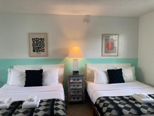 a bedroom with two beds and a lamp on a table at Seaspray Surf Lodge in Vero Beach