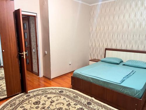 1 dormitorio con cama y puerta con alfombra en Апартаменты с 2 спальнями en Atyraū