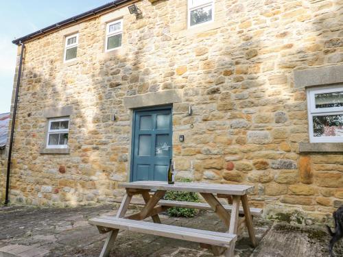 a wooden picnic table in front of a stone building at Todridge Barn in Newcastle upon Tyne