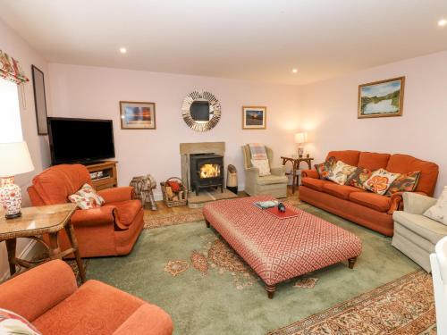 a living room with orange furniture and a fireplace at Todridge Barn in Newcastle upon Tyne