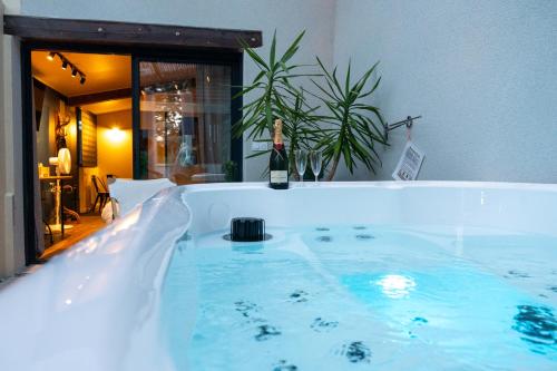 a bath tub with a bottle of wine in it at Yanna Lodge, gîte classé 4 étoiles avec Spa couvert entièrement in Arrest
