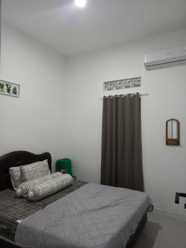 a bedroom with a bed and a window with a curtain at Villa Akela Sukabumi in Sukabumi