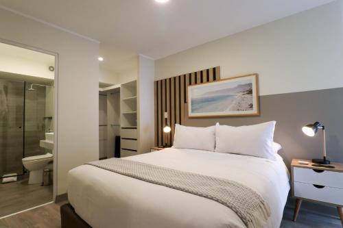 a bedroom with a large white bed and a bathroom at Kennedy by Wynwood House in Lima