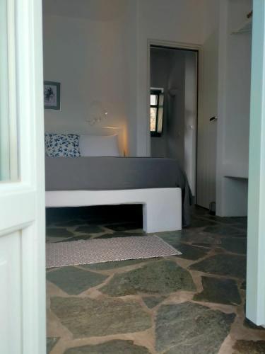 a bedroom with a bed and a stone floor at Amorgos Elegant Houses, Villa 3 in Aegiali