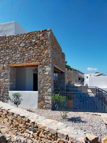 a stone house with a stone wall at Amorgos Elegant Houses, Villa 3 in Aegiali