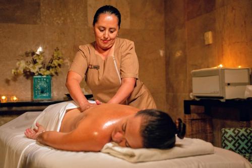 a woman getting a massage from a man on a bed at Wyndham Grand Cancun All Inclusive Resort & Villas in Cancún