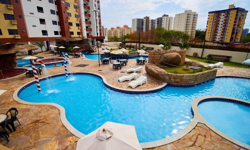 a large swimming pool with chairs and tables and buildings at Golden Dolphin Supreme in Caldas Novas
