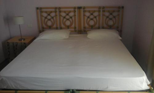 a white bed with a wooden headboard and two pillows at Residencial Las Palmeras de Willy Boca Chica in Boca Chica