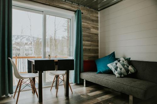 sala de estar con mesa, sofá y ventana en Les Microchalets d'Édouard, en L'Anse-Saint-Jean