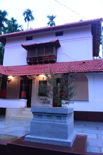 uma casa branca com um telhado vermelho e um edifício em Kaanayi heritage home em Kokkānisseri
