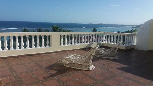 a pair of chairs sitting on a balcony overlooking the ocean at Residencial Las Palmeras de Willy Boca Chica in Boca Chica