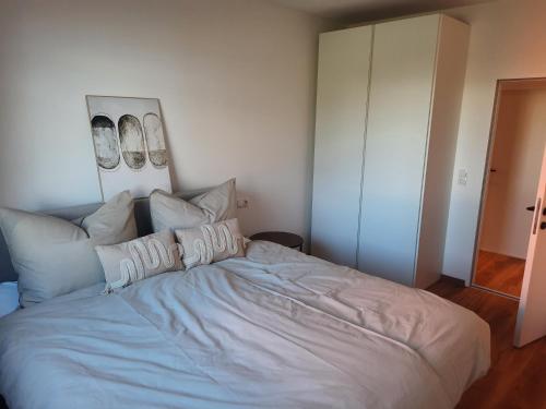 een slaapkamer met een groot bed met witte lakens en kussens bij Apartment by Bruno in Innsbruck