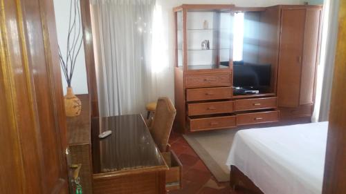 a bedroom with a bed and a desk and a tv at Residencial Las Palmeras de Willy Boca Chica in Boca Chica