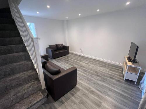 a living room with a couch and a tv and stairs at Perfect for family getaways in West Thurrock