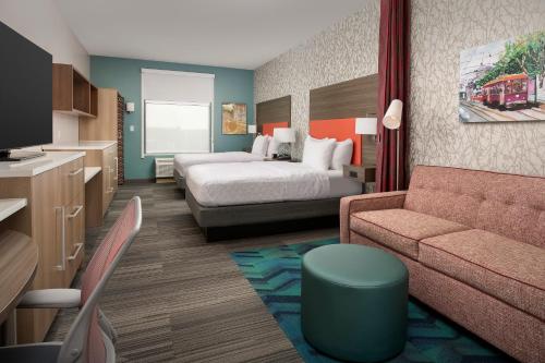 a hotel room with a bed and a couch at Home2 Suites By Hilton Kenner New Orleans Arpt in Kenner