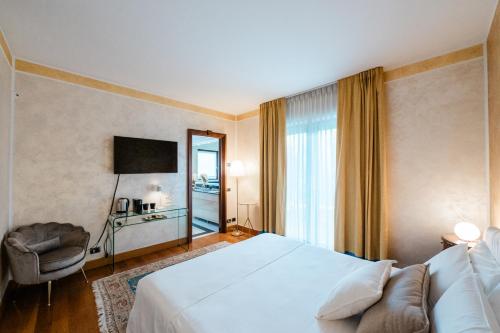 Azzano San PaoloにあるAirport BEA Roomsのベッド、椅子、テレビが備わるホテルルームです。