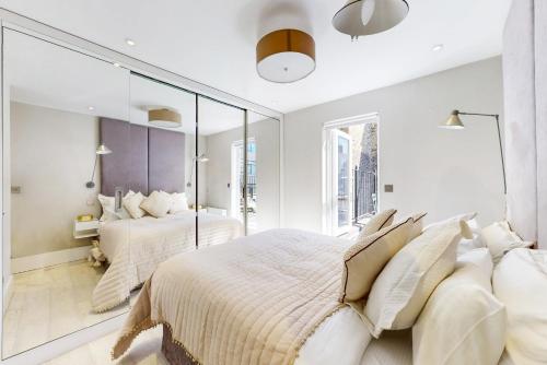 1 dormitorio con 2 camas y un espejo grande en Park Lane Apartments Marylebone en Londres