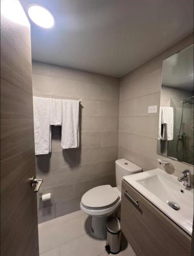 een badkamer met een toilet, een wastafel en handdoeken bij Sweet home in Punta Cana