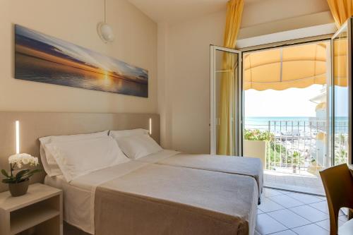 ミザーノ・アドリアーティコにあるSavoia Hotelのベッドルーム1室(ベッド1台付)、スライド式ガラスドアが備わります。
