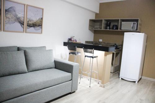 a living room with a couch and a kitchen with a refrigerator at Hotel Águas Virtuosas in Lambari