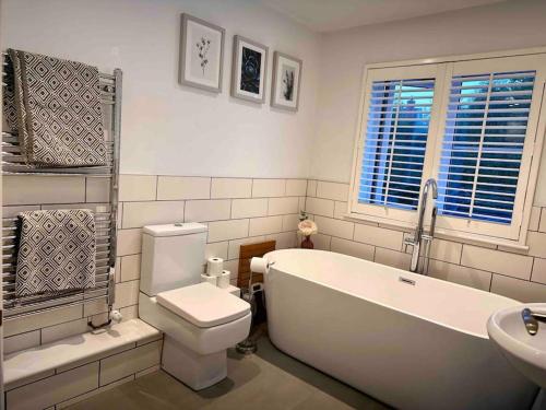 ein Badezimmer mit einer Badewanne, einem WC und einem Waschbecken in der Unterkunft 4 Bedroom Contemporary Home in Hereford in Hereford