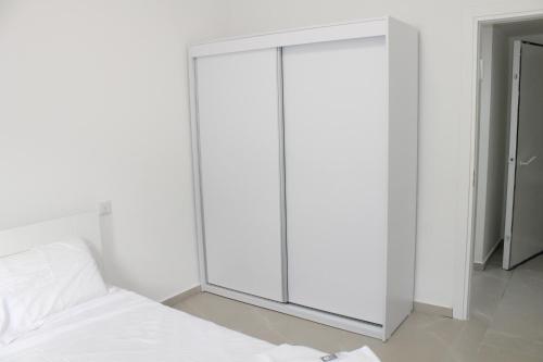 a bedroom with a white cabinet next to a bed at Beach Suite Israel- Private Jacuzzi Sea View Balcony, Off-Site Spa ביץ סוייט ישראל- ג'קוזי פרטי עם נוף ים, אפשרות לספא מוזל in Ashqelon