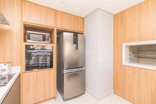 a kitchen with a stainless steel refrigerator and a microwave at Apto Supreme PUC in Porto Alegre