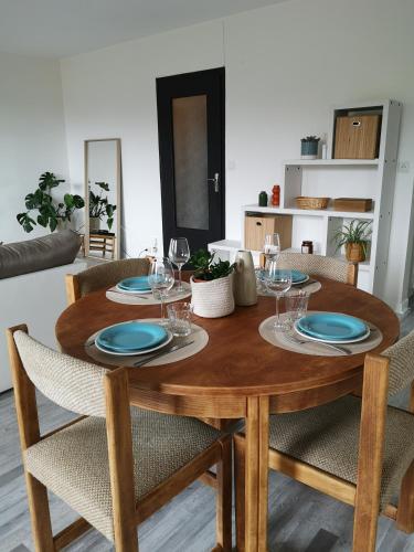 une table en bois avec des assiettes et des verres à vin dessus dans l'établissement Appartement avec garage proche du centre-ville, à Troyes
