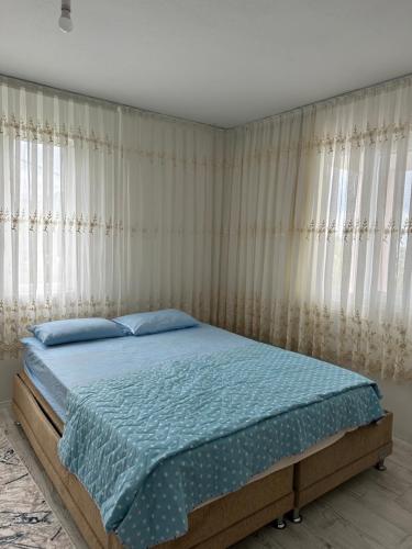 a bedroom with a bed with blue sheets and curtains at Tirebolu Kaplan Apartman 