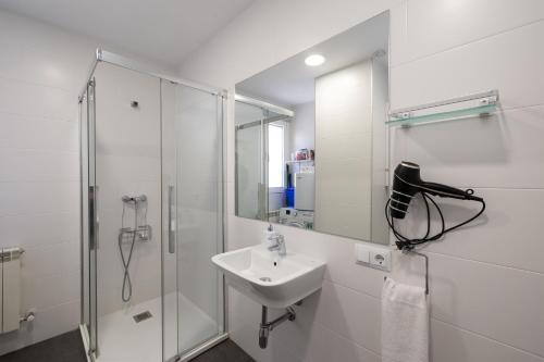 uma casa de banho branca com um lavatório e um chuveiro em ALQUILAZ Apartamentos Turísticos em Zamora