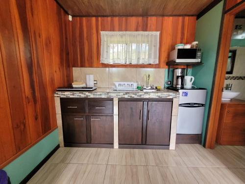 a kitchen with wooden cabinets and a white refrigerator at Cabañas Sueños del Arenal in Fortuna