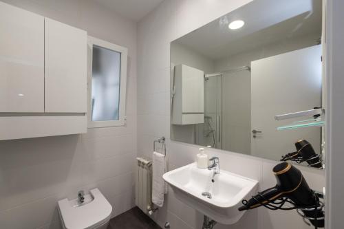 La salle de bains blanche est pourvue d'un lavabo et d'un miroir. dans l'établissement ALQUILAZ Apartamentos Turísticos, à Zamora