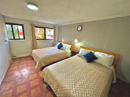 um quarto com duas camas e um relógio na parede em Urban Hotel em Guatemala